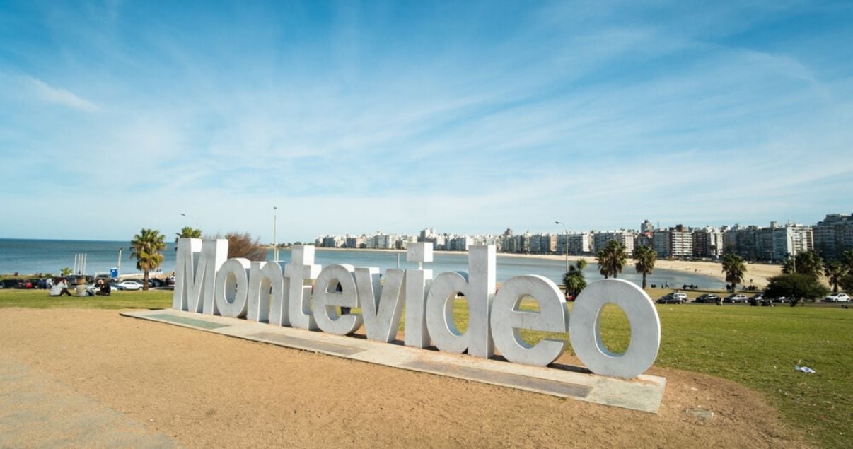 Montevideo escrito en letras gigantes con los barrios del este de fondo y el acceso a la ciudad