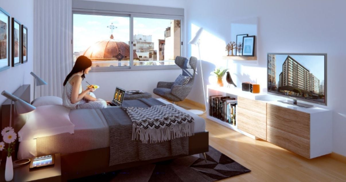 Mujer joven mirando su computadora en la cama en un apartamento de Pinto Turovlin estudio de arquitectos