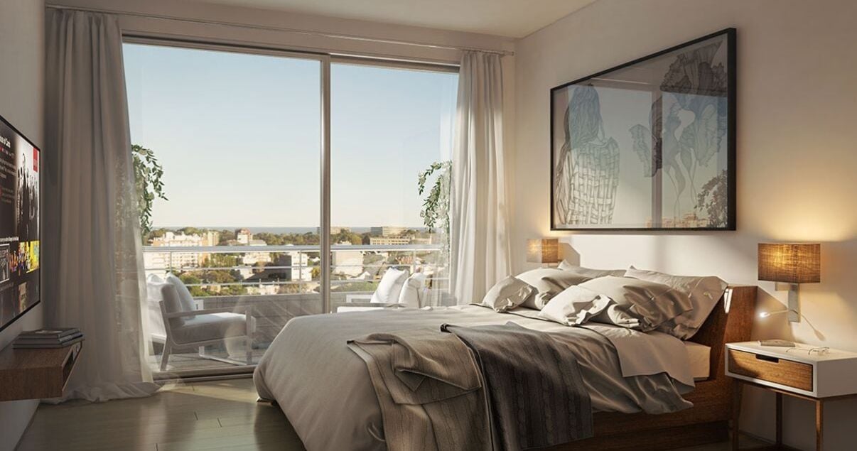 Dormitorio con cama y balcón en el interior de un apartamento en el edificio 01 Parque Batlle de la empresa constructora Nova